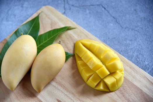 Tropical Fruits. Fresh and beautiful mango fruit set in a wooden with sliced diced mango chunks on a dark background. Selected focus