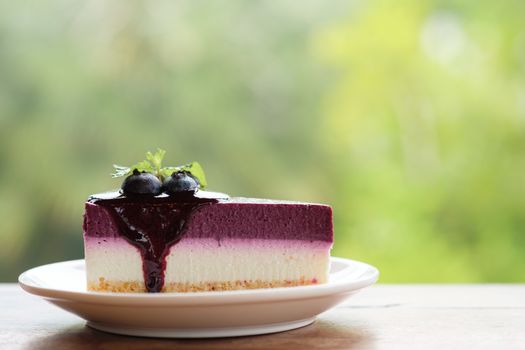 Blueberry Mousse Cake Topped with  fresh Blueberries and mint leaves.