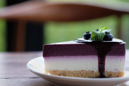 Blueberry Mousse Cake Topped with  fresh Blueberries and mint leaves.