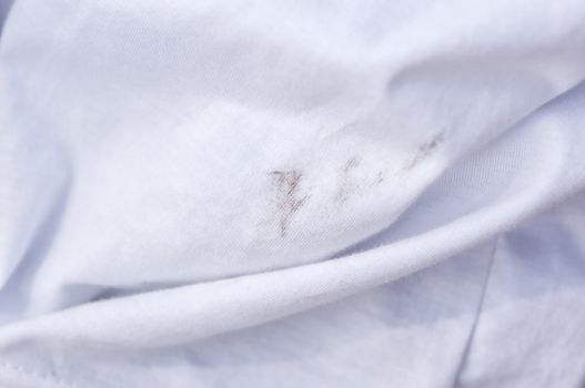 Black stains on white fabrics, Dirty  stain on fabric from accident in daily life. Concept of cleaning stains on clothes or cleaning the house. Selected focus