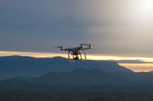 The drone with the professional camera takes pictures of the misty mountains at sunset. Uav drone copter flying with digital camera. Hexacopter drone with high resolution digital camera on the sky.