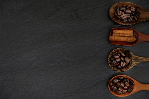 Roasted coffee beans  in wood spoons on rustic black background
