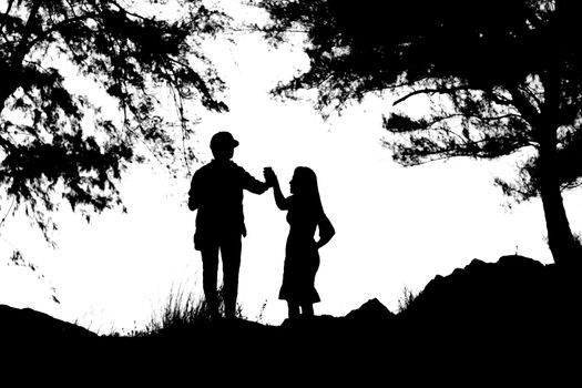 Silhouettes of a women and a man are holding hand under the tree.