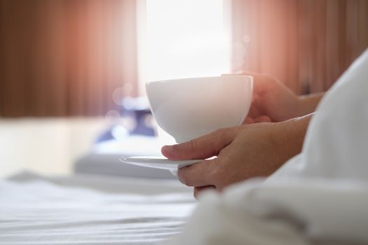 Women are drinking coffee on the bed in the morning.