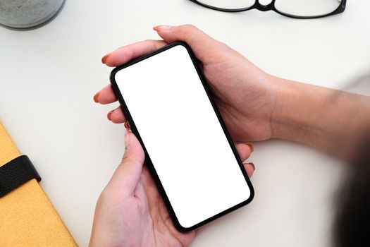 Top view Woman sitting and holding blank screen mock up mobile phone.