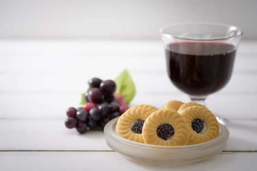 Blueberry Biscuits put on a ceramic plate and bunch of purple grapes placed close together on white wooden background, Selective focus.