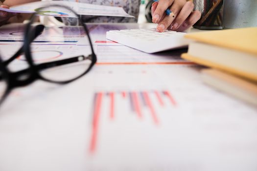 Close up of accountant hand holding pen working on calculator to calculate business financial reports, accountancy document at office, business financial concept