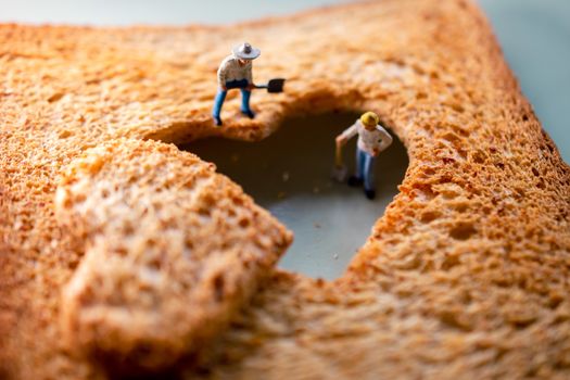 Love Concept. Sad Relationship. Group of Worker Miniature Fixing a Burned Sliced Toasted Bread with a shape of Heart