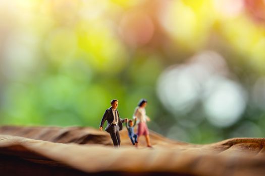 Love and Happy Family. Work Life Balance Concept. Miniature of Father, Mother and Son holding Hands and Walking on Dry Leaf in Park