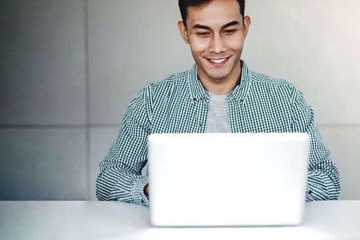 Happy Young Businessman Working on Computer Laptop in Office. Smiling and looking at Computer Screen