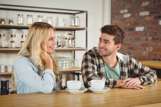 Smiling hipster sitting and talking at coffee shop