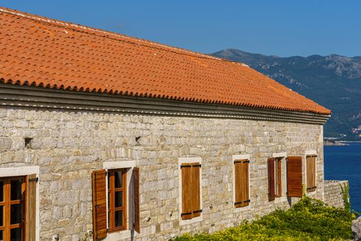 Architecture of the Balkan countries. The building is made of stone with a tiled roof and wooden shutters on the windows.