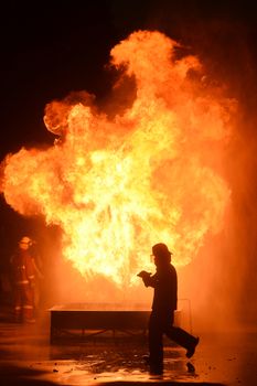 firefighters with fire hose fight with fire at night