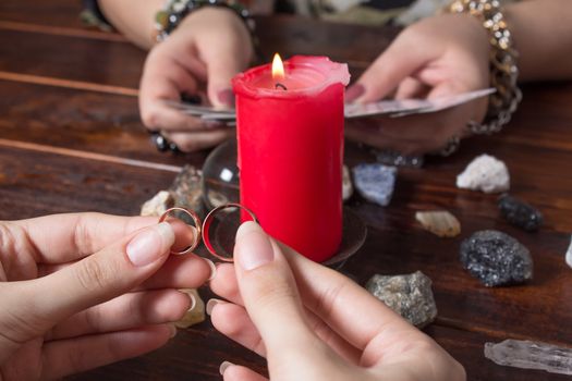 A Gypsy woman guesses a love match using wedding rings and fortune-telling cards by candlelight.Fortune telling with wedding rings, fortune telling for Christmas for love.Spiritism and magic sessions