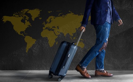 Travel Concept. Young Person with Luggage Walking by the Wall. World Map as background