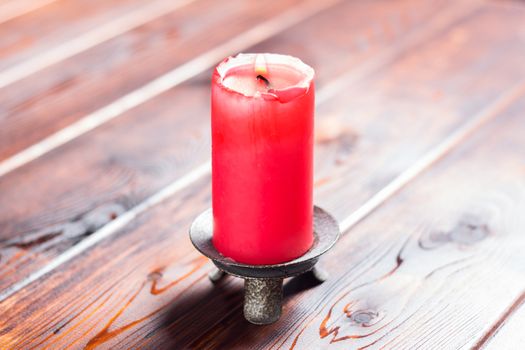 burning old candle with vintage brass candlestick on wooden background in minimalist room interior with copy space. A burning candle stands on a wooden table. A red lighted candle