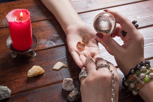 A fortune teller predicts the fate of love with wedding rings, a magic ball, lighted candles and magic stones. A Gypsy woman performs a love spell. A clairvoyant palmist reads by hand with a candle.