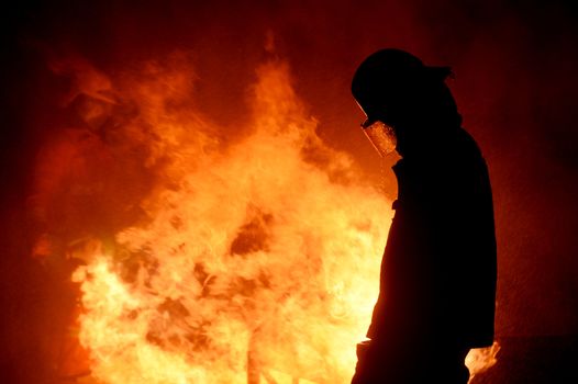 firefighters with fire hose fight with fire at night