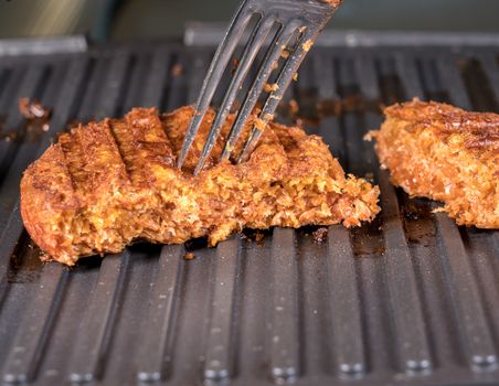 Close shot of the meat like plant-based patties for vegetarian beef burgers being grilled on hot griddle