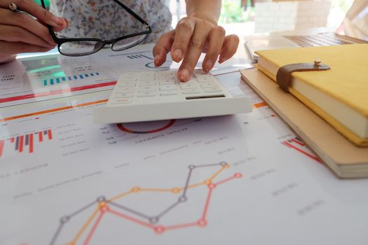 Close up of businessman or accountant hand holding pencil working on calculator to calculate financial data report, accountancy document and laptop computer at office, business concept