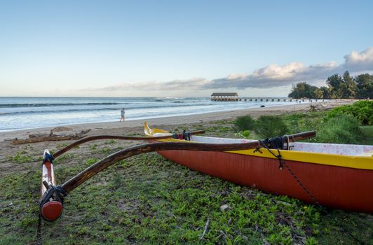 Traditional hawaiian canoe on beach by the pier on Hanalei Bay in Kauai
