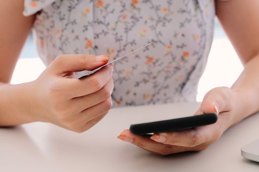 Close up hand of woman using smart phone and holding credit card for online shopping - Online Payment Concept