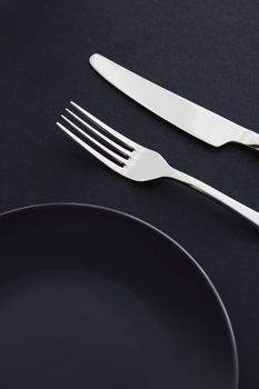 Empty plates and silverware on black background, premium tableware for holiday dinner, minimalistic design and diet concept