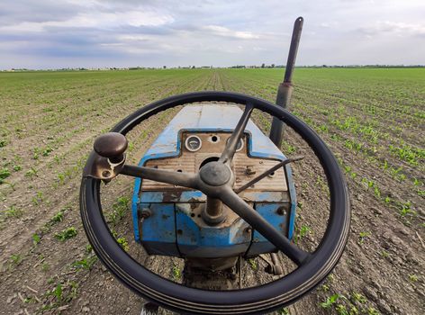 Dashboard of an Old rusty tractor in fields during spring time