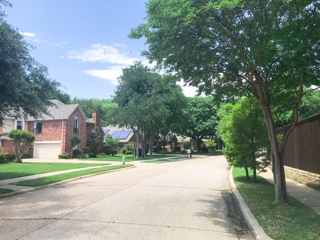 Typical upscale suburban residential neighborhood near Dallas, Texas, America with solar panel roof house and mature trees.