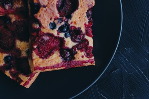 Berry pie on black plate, rustic homemade food with organic ingredients on black background