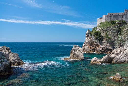 Kayakers or canoeists in the sea by the city walls and old fort Lawrence in Dubrovnik