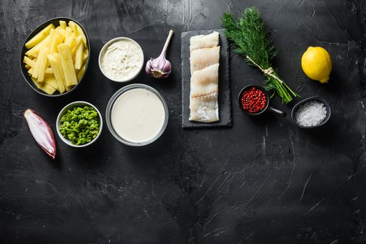 Traditional fish and chips ingredients recipe raw cod fillets on stone slate batter, potatoe, tartar sauce, minty mushy peas, lemon , shallot, mint, garlic, salt, peppercorns on black stone background concept top view space for text.