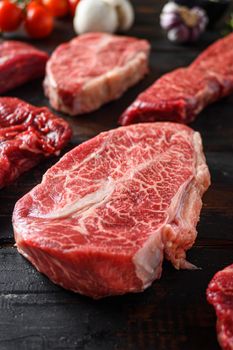 Alternative black angus cut top blade steak close up in front of other cuts in butchery on old wood table side view selective focus.