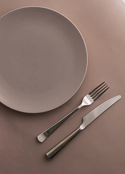 Empty plate and cutlery as mockup set on brown background, top tableware for chef table decor and menu branding design