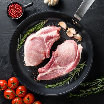 Pork belly Farm fresh cutlet with oil and spices for grill and ingredients for cooking on black skillet over dark black slate background top view square