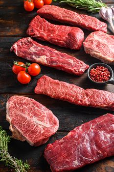 Set of fresh raw alternative beef steaks flap flank Steak, machete steak or skirt cut, Top blade or flat iron beef and tri tip, triangle roast with denver cut side view over old butcher wood table close up.