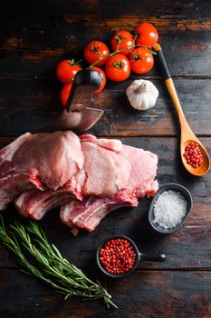 Bio Pork Chops from organic farm with spices: pepper, salt, bay leaf. Butcher chopping cleaver in wood table over rustic wood and metal Food background top view