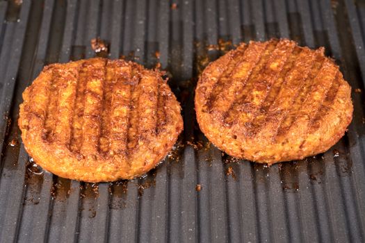 Close shot of the meat like plant-based patties for vegetarian beef burgers being grilled on hot griddle