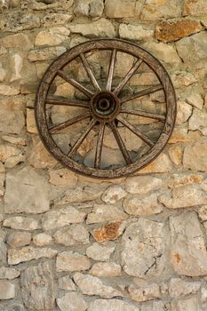 Old wooden cart wheel on stone farmhouse wall