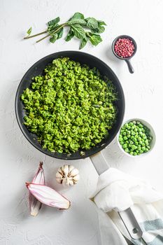 Mushy peas recipe cooked frying pan and peas in bowl with mint shallot pepper and salt over white stone surface top view organic keto food lat flay overhead photo.