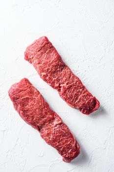 Raw set of denver steak on a white stone background vertical.