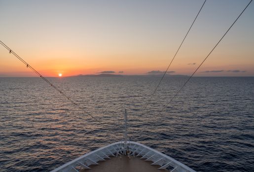 Small cruise liner sailing across the ocean as dawn starts to light the sky