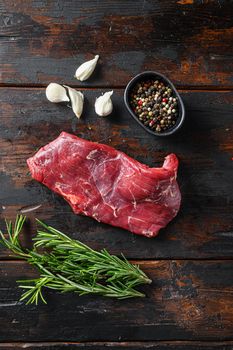 Flank, Bavette steak with seasonings, and fresh herbs raw meat, marbled beef . Dark wood rustic background. Top view.