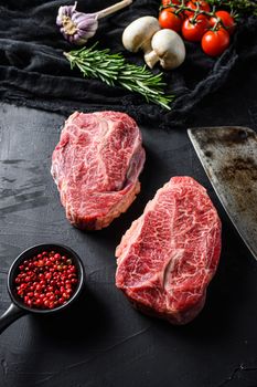 Raw top blade cut organic meat ner butcher meat clever knife for bbq or gtrill top view over black stone background close up vertical selective focus.