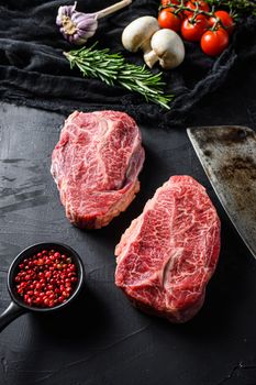 Raw top blade cut organic meat ner butcher meat clever knife for bbq or gtrill top view over black stone background close up vertical selective focus.