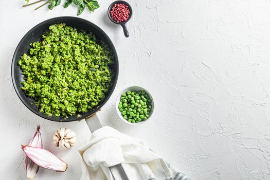 Mushy peas recipe cooked frying pan and peas in bowl with mint shallot pepper and salt over white stone surface organic keto food top view lat flay overhead photo space for text.