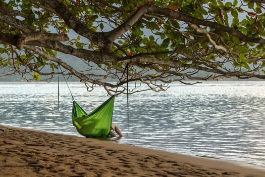Rear view of romantic couple enjoying sunset in Kauai from hanging swinging hammock