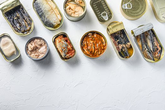 Cans with different preserve of fish and conserve seafood, opened and closed cans with Saury, mackerel, sprats, sardines, pilchard, squid, tuna, over white stone surface top view space for text.