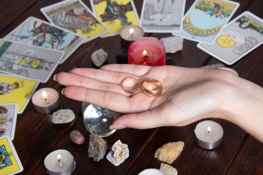 Bangkok,Thailand,March.15.20.The girl holds wedding rings on her hand with Tarot cards,crystals,a magic ball and a lighted candle.Fortune telling and fortune telling for love, the rite of love spell