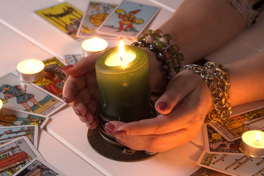 Bangkok,Thailand,March.15.20.Female hands hold a lighted candle in the dark at night. A fortune teller performs a magical. Ritual of enchantment and clairvoyance. Seance and prediction of the future